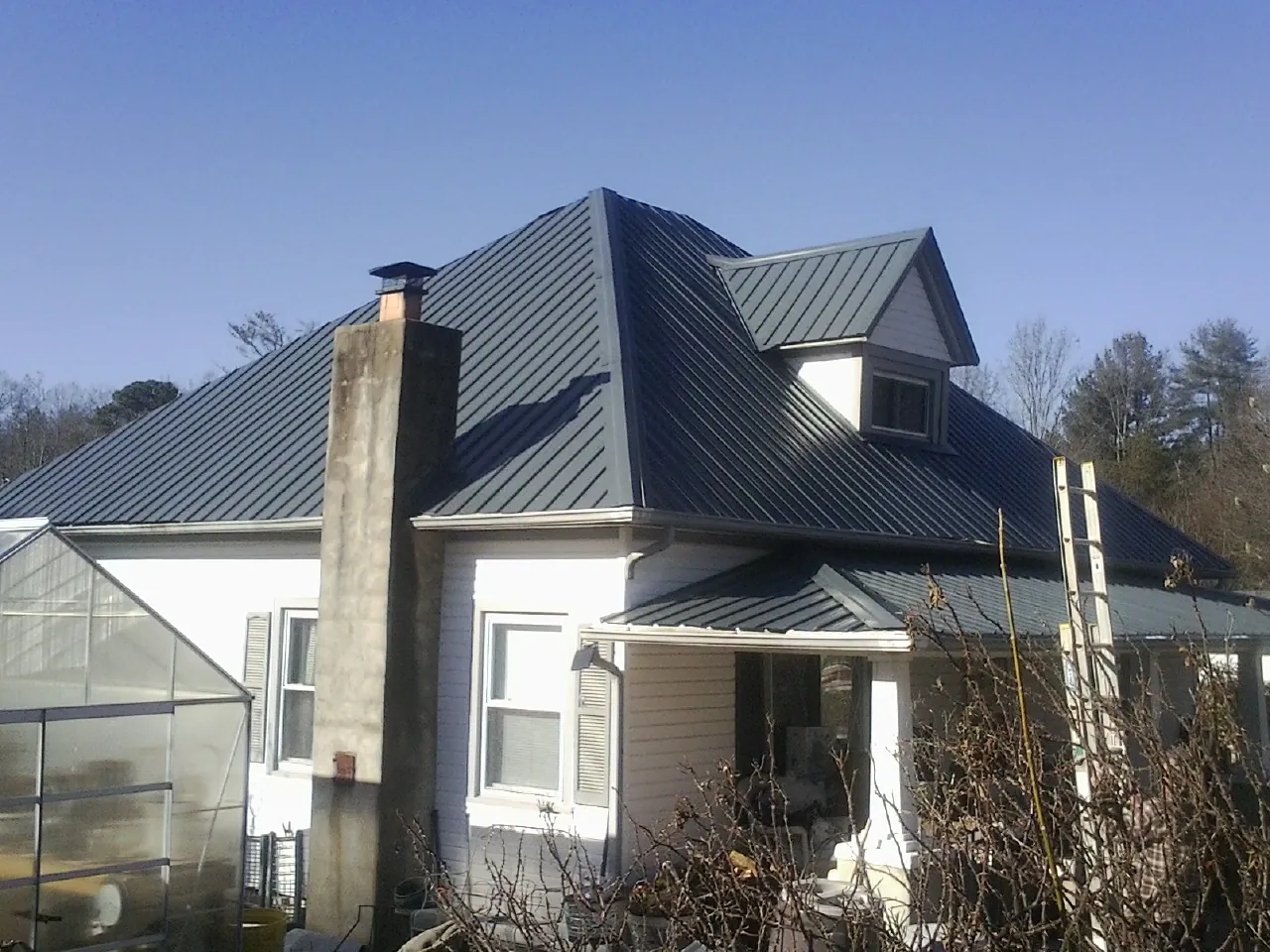 Dark blue standing seam metal roof on a white farmhouse with dormer — Slate & Tile Roof Repair by Roofing Brothers in Westbrookville