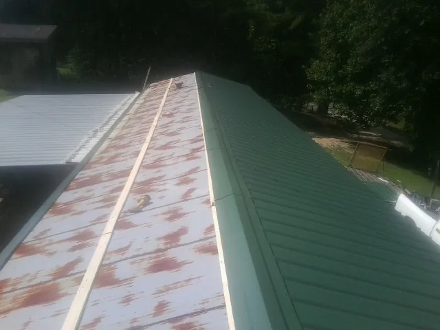 Old rusted panels beside newly installed green metal roofing — Wind Damage Roof Repair by Roofing Brothers in Westbrookville