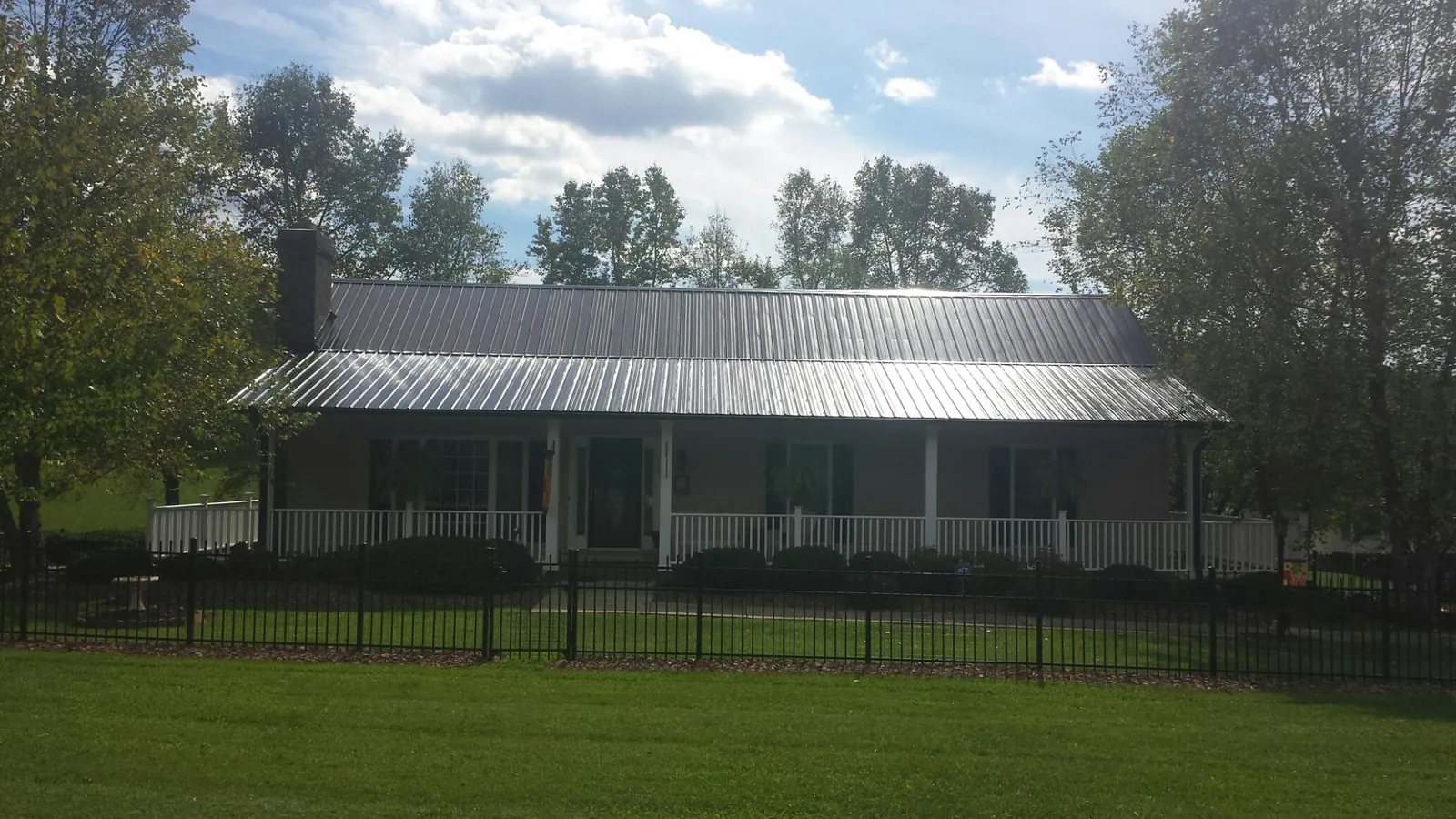 Gray metal roof on a brick ranch with a full width front porch — Gutter Guard Installation work by our crew in Westbrookville