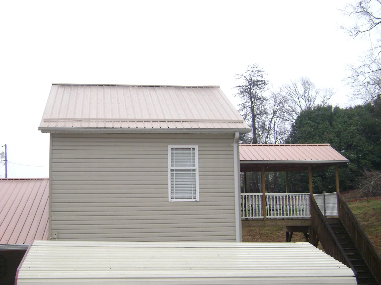 Tan metal roofs on a two story addition and attached porch, from a Roof Replacement job in Westbrookville