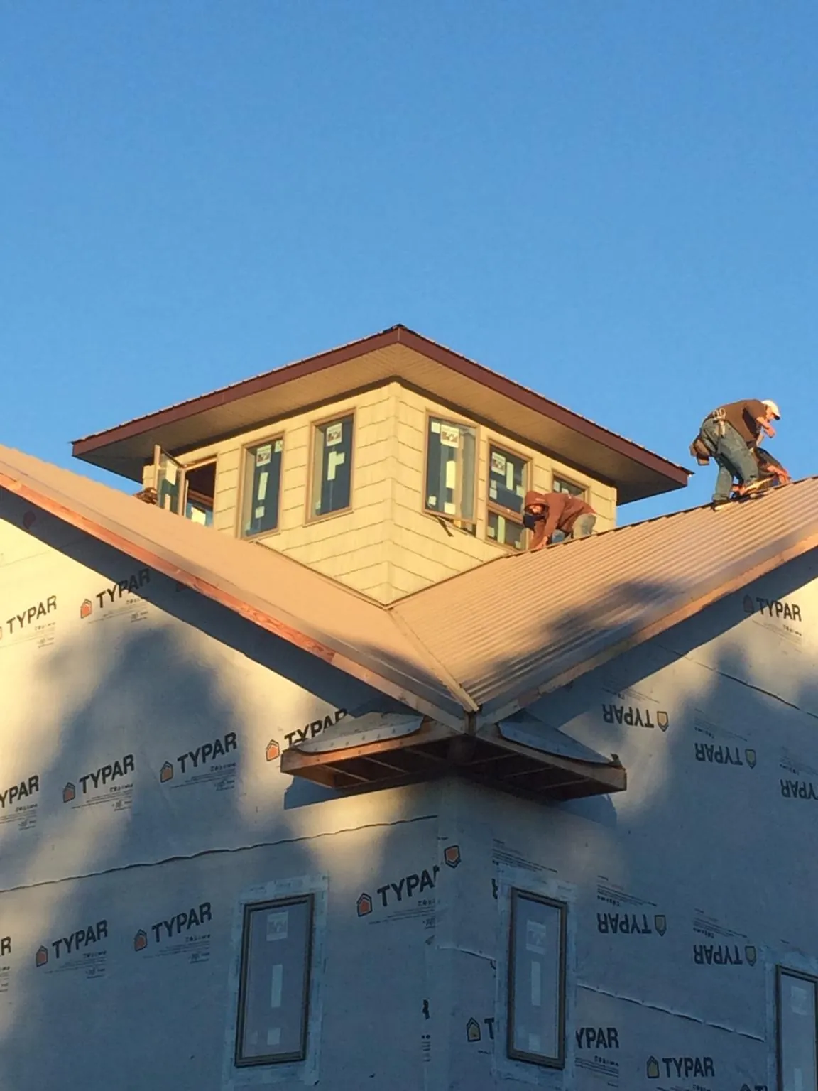 Roofers working around a rooftop cupola on a new metal roof at sunset — Roof Waterproofing in Westbrookville by Roofing Brothers